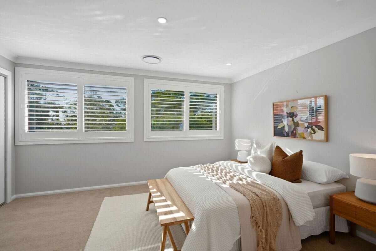 Guest bedroom with plantation shutters and timber nightstands