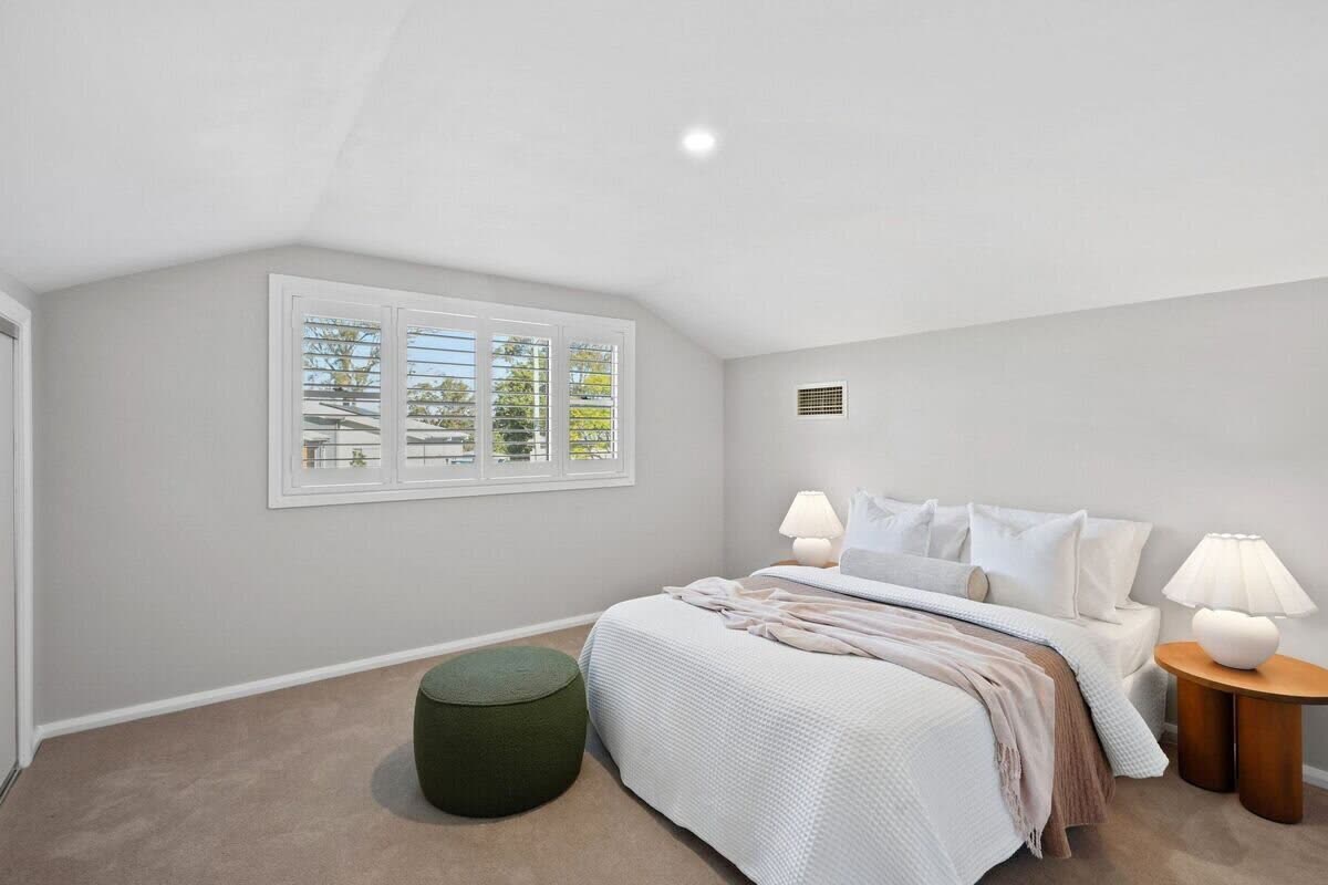 Upper bedroom with vaulted ceiling and olive ottoman
