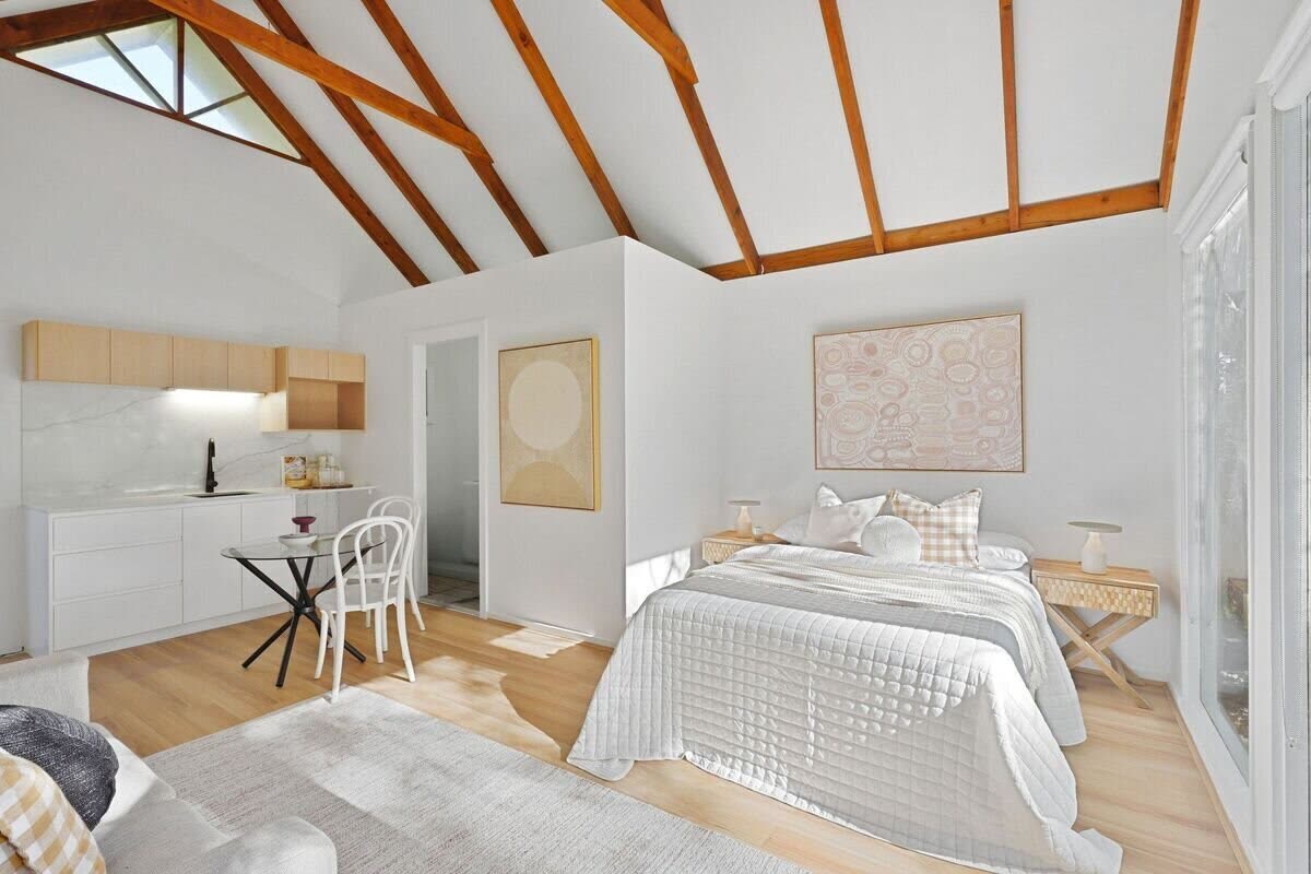 Studio interior — kitchenette, dining and sleeping zone under vaulted timber ceiling